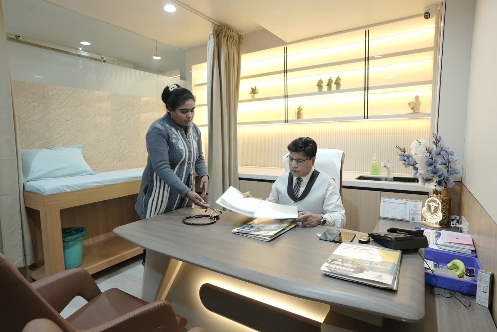 A doctor reviews papers with a colleague in a consultation room at Paliwal Hospital